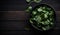 Fresh Spinach in a Black Bowl on a Wooden Table, Copy Space