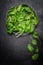 Fresh spinach leaves in metal bowl on dark background