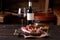 Fresh split lamb ribs on a cutting board with a sealed bottle of red wine and a glass of wine, olive oil with red pepper