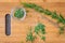 Fresh sprigs of rosemary with on a bamboo cutting board, paring knife, rosemary leaves, chopped rosemary in small glass bowl