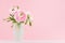 Fresh spring buttercup flower bouquet in exquisite glass vase on white wood table and pastel pink color background.