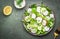 Fresh spring crispy salad with radishes, cucumbers, lettuce and green onions with greek yogurt dressing, green table background,