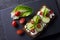 Fresh spring sandwich on a sliced gluten free sunflower bread. Red and green vegetables on black slate. Cucumber, chili and