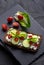 Fresh spring sandwich on a sliced gluten free sunflower bread. Red and green vegetables on black slate. Cucumber, chili and