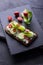 Fresh spring sandwich on a sliced gluten free sunflower bread. Red and green vegetables on black slate. Cucumber, chili and