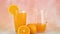 Fresh squeezed orange juice in glass and jug on pastel background with sliced orange