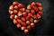 Fresh strawberries array heart shape on black background. Love concept. Valentine`s Day Concept. Winter Concept.