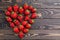 Fresh strawberries array heart shape on old wooden background.