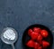 Fresh strawberries on black plate with sugar strainer on grey background