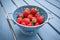 Fresh strawberries in a blue colander on the table