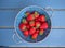 Fresh strawberries in a blue colander on the table