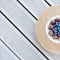 Fresh strawberries and blueberries lie in a plate on a straw round substrate on terrace boards on the veranda. Food concept, flat