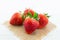 Fresh strawberries on burlap and white wood background with selective focus point