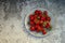 Fresh strawberries in a plate on a gray concrete table