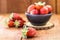 Fresh strawberries on rustic wooden background, in handmade clay bowl, space for text