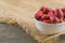 Fresh strawberries in white bowl with sackcloth on table