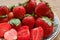 Fresh strawberries with a white ornate ceramic plate on the brown table