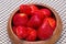 The fresh strawberries in the woonden bowl on the mat.