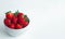 Fresh strawberry with green leave head in a white marble porcelain bowl on white background with copy space, for banner