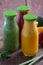 Fresh strawberry, orange and broccoli smoothie in bottles with fruits and vegetables on a brown wooden rustic background. vertical