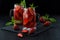 Fresh strawberry smoothie. Fresh summer cocktail with strawberries and ice cubes on a dark background on a black wooden table