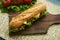Fresh submarine sandwiches on dark wooden cutting board