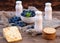 Fresh summer blueberry with leaf in white bowl, yogurts bottles on the brown wooden background