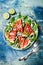 Fresh summer grilled watermelon salad with feta cheese, arugula, onions on blue background.