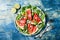 Fresh summer grilled watermelon salad with feta cheese, arugula, onions on blue background.