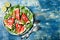 Fresh summer grilled watermelon salad with feta cheese, arugula, onions on blue background.