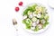 Fresh summer salad with radishes, cucumbers, lettuce and green onions with greek yogurt dressing, white table background, top view