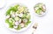 Fresh summer salad with radishes, cucumbers, lettuce and green onions with greek yogurt dressing, white table background, top view