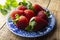 Fresh summer Strawberry in blue vintage plate on rustic wooden background with copy space. Close up berry, breakfast or healthy