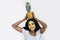 Fresh summer studio shot of joyful African girl in white t-shirt with pineapple on head, having cleaning golden facial