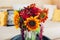 Fresh sunflowers and zinnia flowers put in vase in living room. Interior and home decor. Bouquet of fall blooms on table