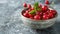 Fresh sweet cherries bowl with leaves in water drops on blue stone background, top view