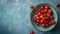 Fresh sweet cherries bowl with leaves in water drops on blue stone background, top view