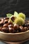 Fresh sweet edible chestnuts in wooden bowl on table, closeup