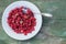 Fresh sweet raspberry lies in a plate and spoon berry which is on an old wooden table