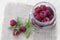 Fresh sweet red raspberry in a glass jar and mint on light wooden table