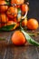 Fresh tangerine clementines with leaves on dark wooden background.