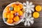 Fresh tangerines in dish, christmas balls, artificial snowflakes on wooden table. Top view