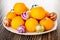 Fresh tangerines in dish, christmas balls on wooden table