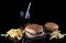 fresh tasty burgers, cola and french fries on black glass table with reflection