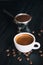 Fresh tasty espresso cup of hot coffee with coffee beans and Coffee maker on dark background