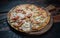 Fresh tasty pizza with seafood, tomato, paprika and mozzarella cheese on rustic wooden background