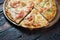 Fresh tasty pizza with seafood, tomato, paprika and mozzarella cheese on rustic wooden background