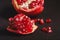 Fresh tasty sweet peeled pomegranate with red seeds on dark black background, macro angle view