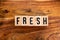 ` FRESH ` text made of wooden cube on  wooden background