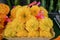 Fresh Thai style flower garlands made of bright yellow marigold with pink ribbon selling on basket in local market